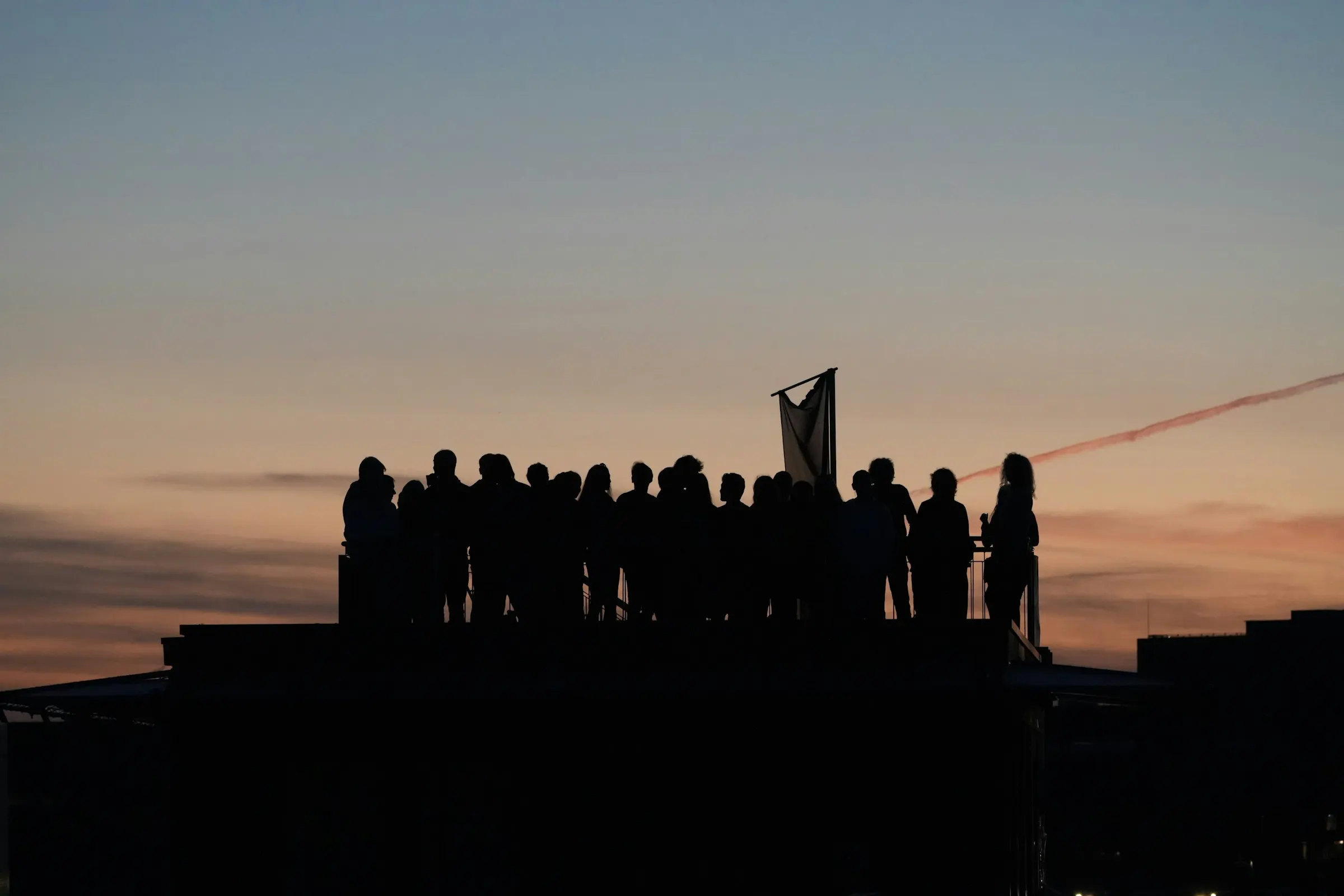 A crowd at dusk holding a banner